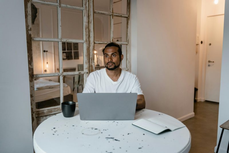 New immigrant sitting at a table with a coffee and notebook feeling overwhelmed about money in Australia