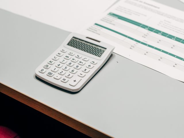 A payslip and calculator on a desk