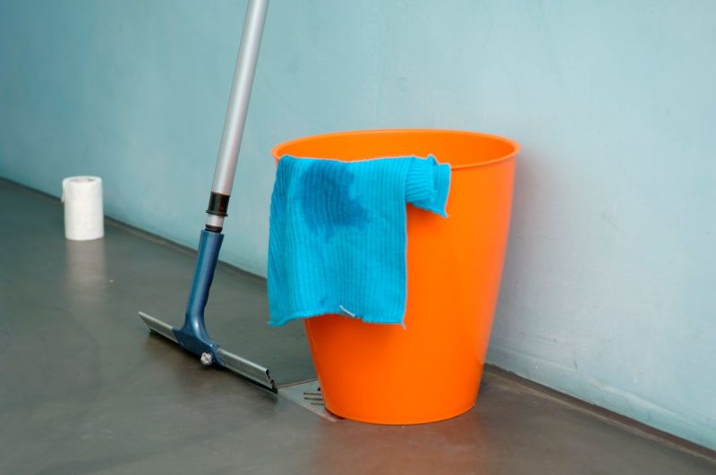 A bucket placed on the floor catching drips from a leaking ceiling