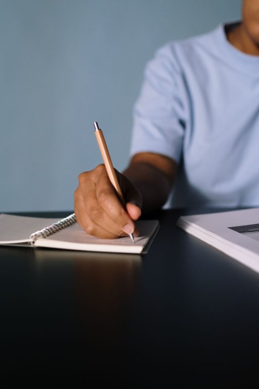 A person writing a written repair request at a desk