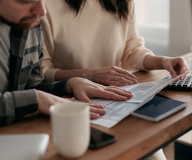 Couple reviewing paperwork together at home, saving for a house