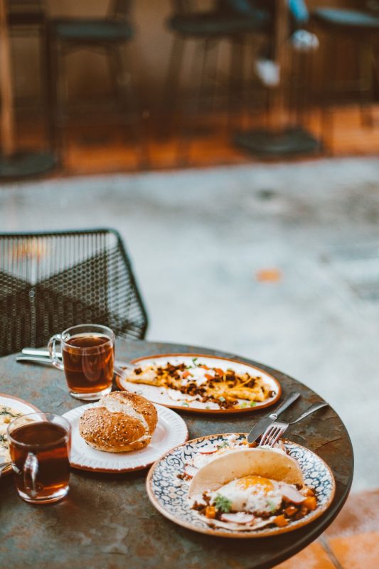 Cafe table with coffee and plates, a reminder of hidden costs in Australia for new immigrants