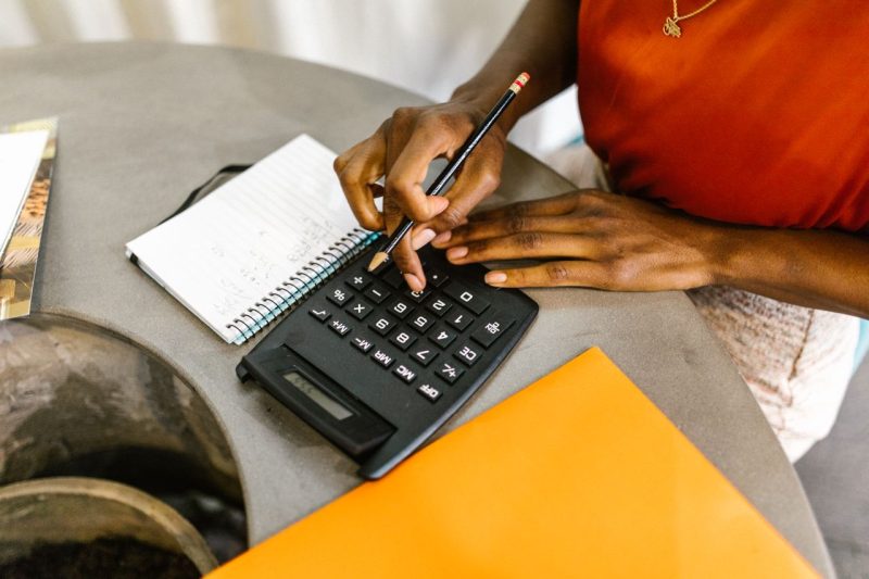 Notebook and calculator on a table with a list of monthly costs