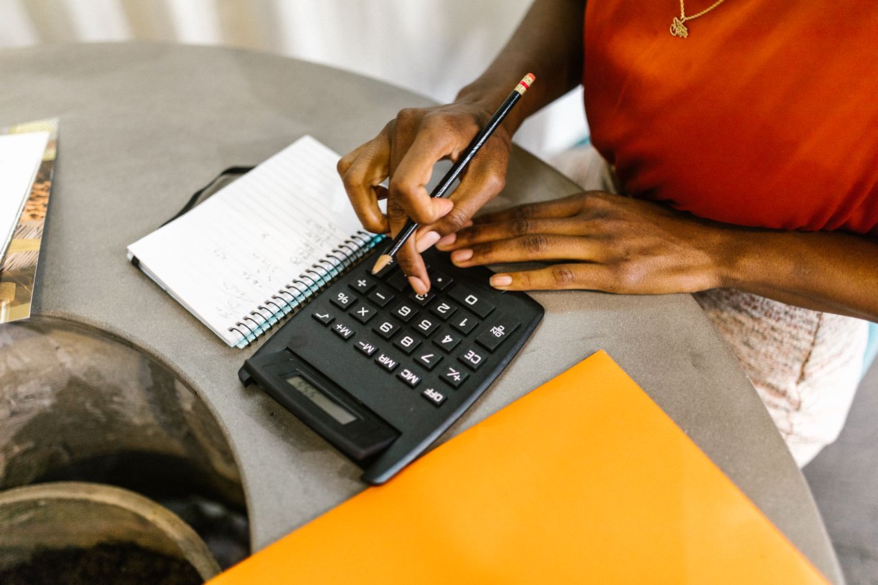 Notebook and calculator on a table with a list of monthly costs