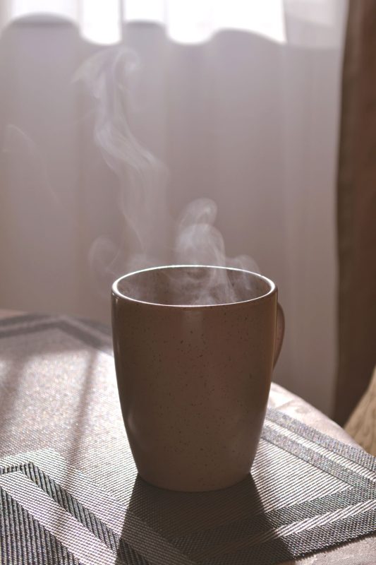 Cup of tea on a table beside a window in morning light